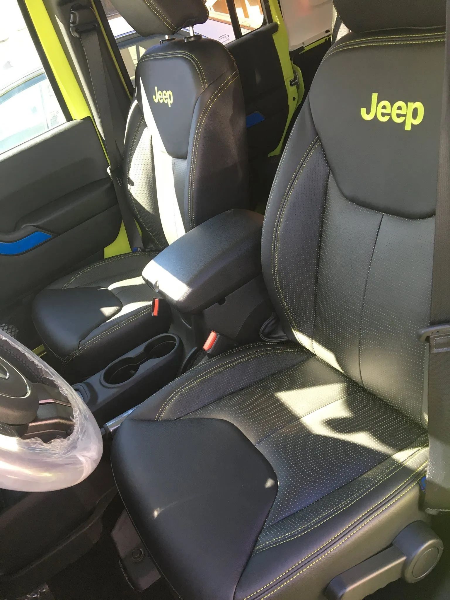 Jeep vehicle interior with black front seats and center console, featuring bright yellow Jeep logos on the seatbacks