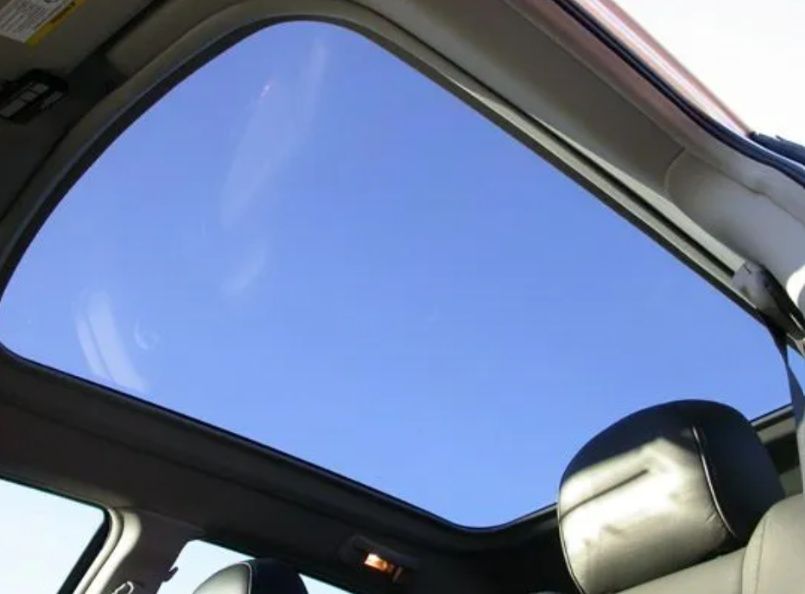Car interior with a large sunroof showing a blue sky above the front seat