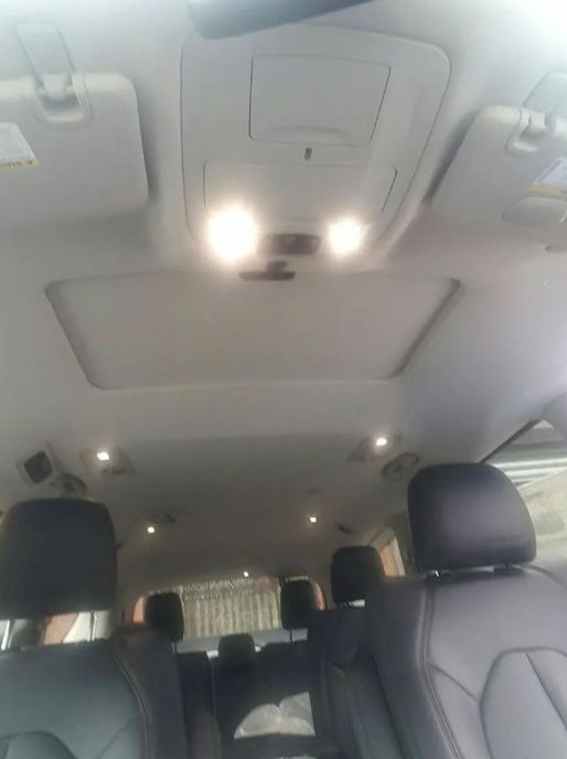 Inside a minivan, showing gray seats and ceiling lights from the rear passenger area