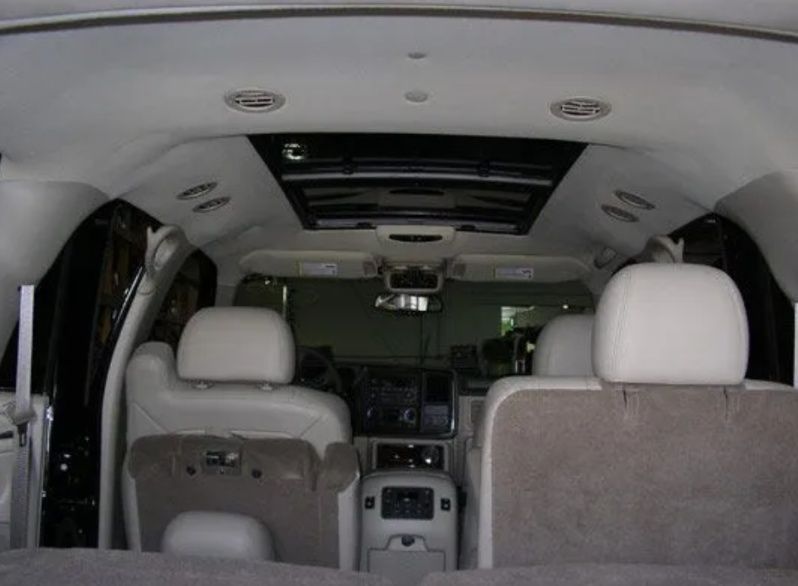 Interior of a white SUV, showing front and rear seats, dashboard, and open sunroof.