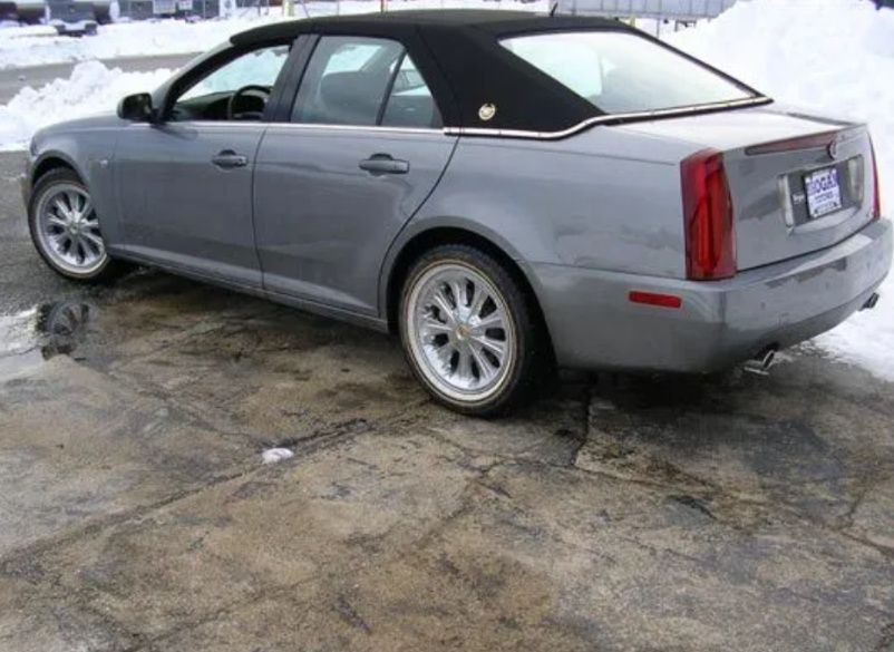 Silver coupe parked on wet pavement, seen from the rear-left side