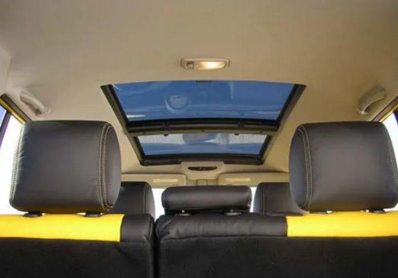 Car interior with rear seats and a sunroof open to the blue sky