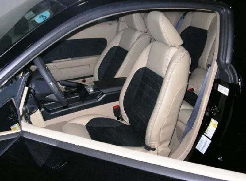 Luxury car interior with cream and black leather front seats and dashboard visible