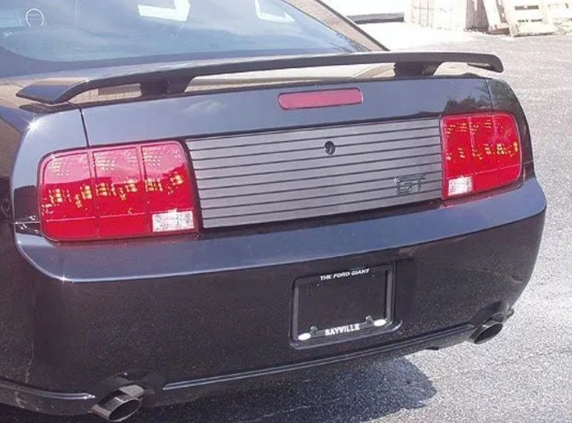 Rear view of a black Ford Mustang with red taillights and a silver trunk panel