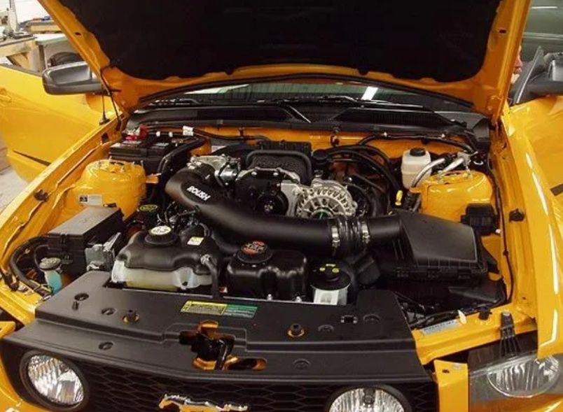 Yellow sports car with hood open, showing a detailed engine compartment
