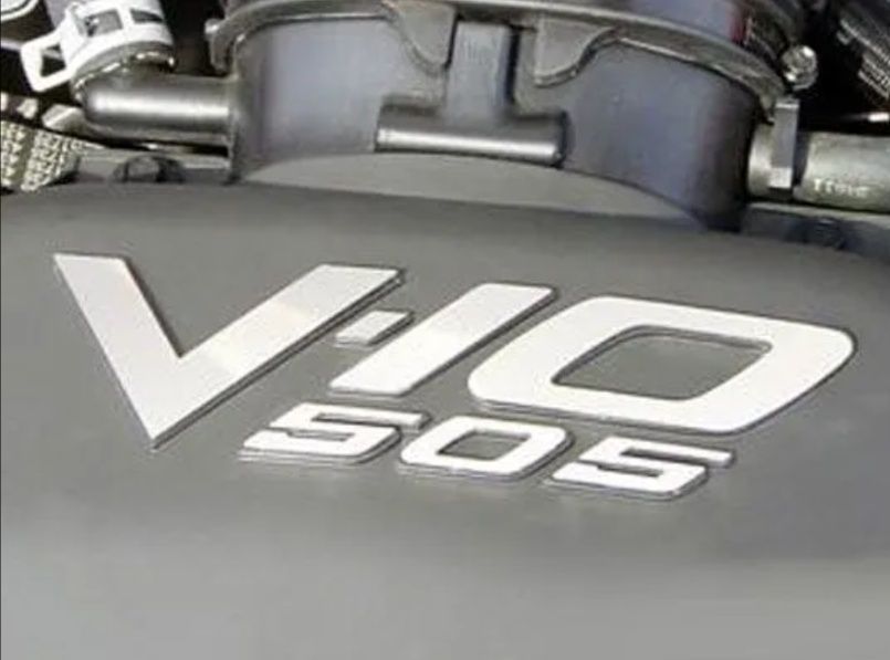 Close-up of a car engine cover labeled “V10 5.0S” in silver lettering.