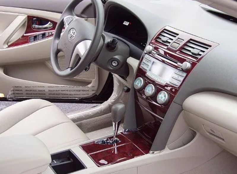 Luxury car interior with beige seats, wood trim, and a steering wheel view of the dashboard and center console