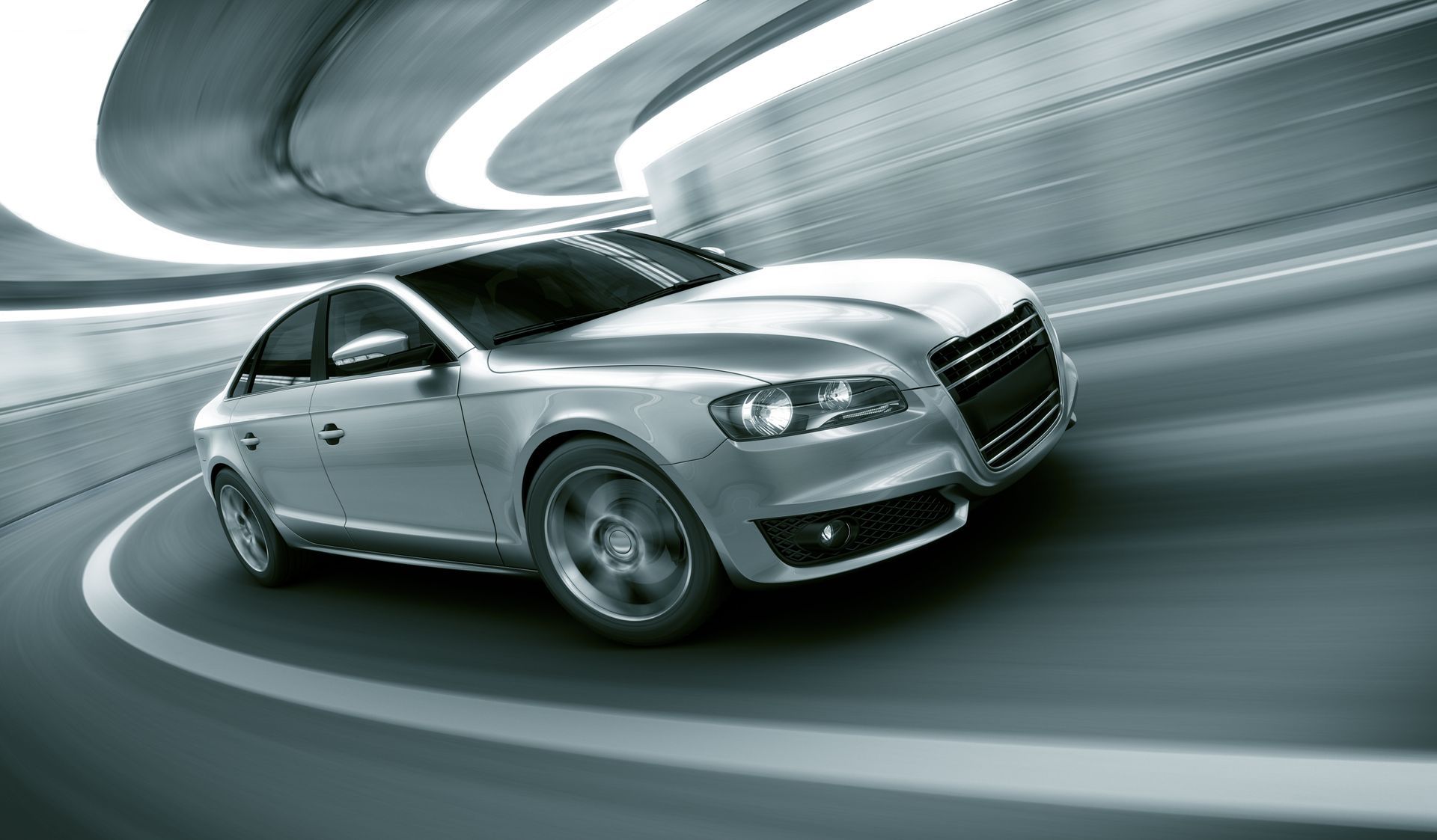 Silver sedan speeding through a tunnel with blurred motion lines, implying speed.