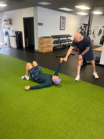 A man is helping a woman lift a barbell in a gym