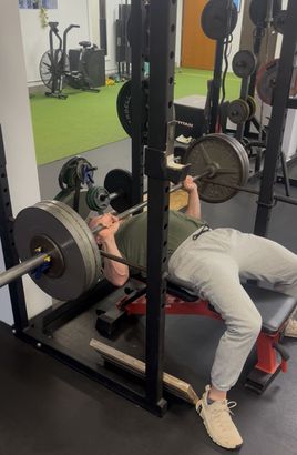A man is jumping in the air in a gym next to a tape measure.