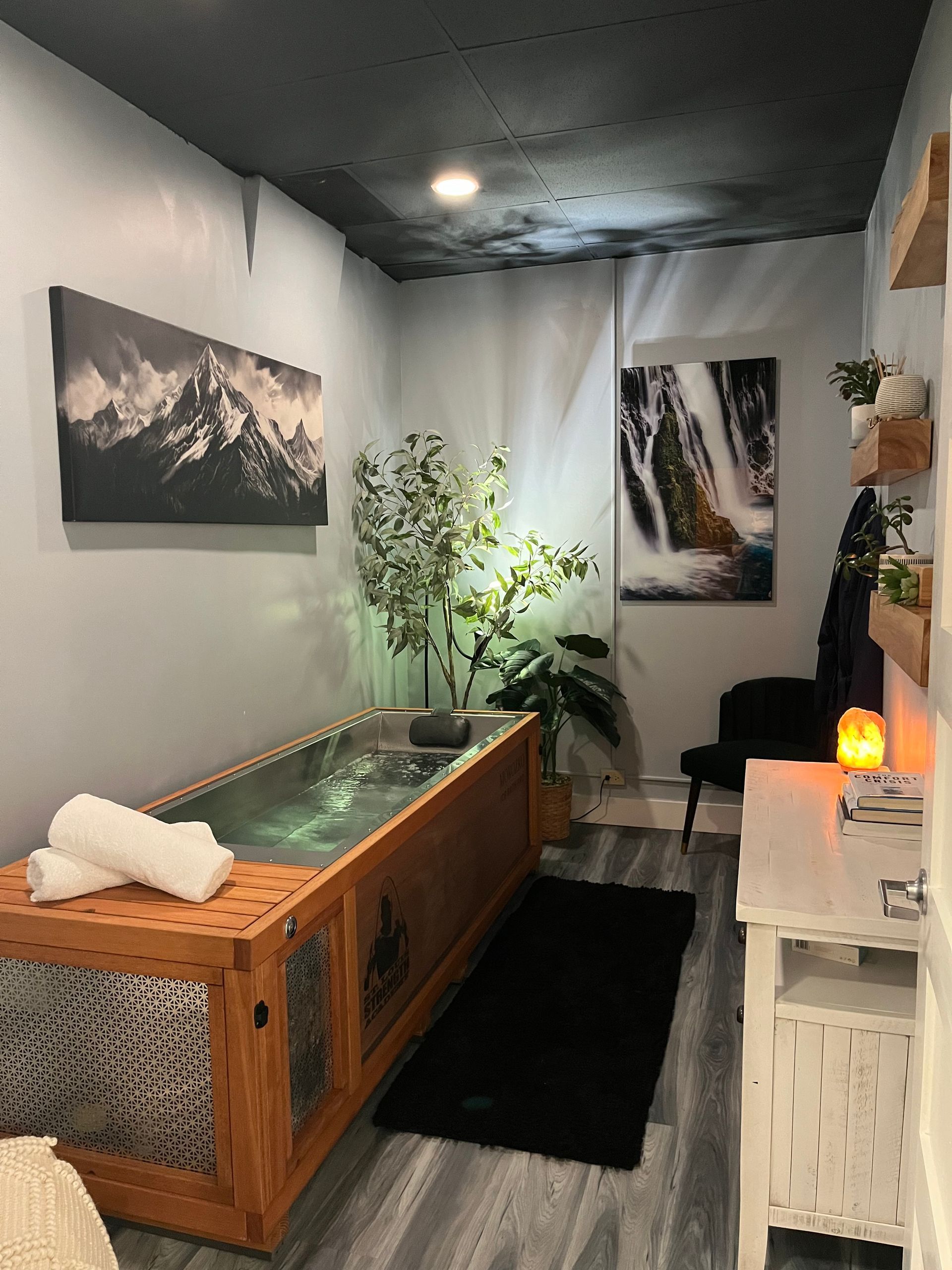 An ice bath with a wooden tub and a painting on the wall.