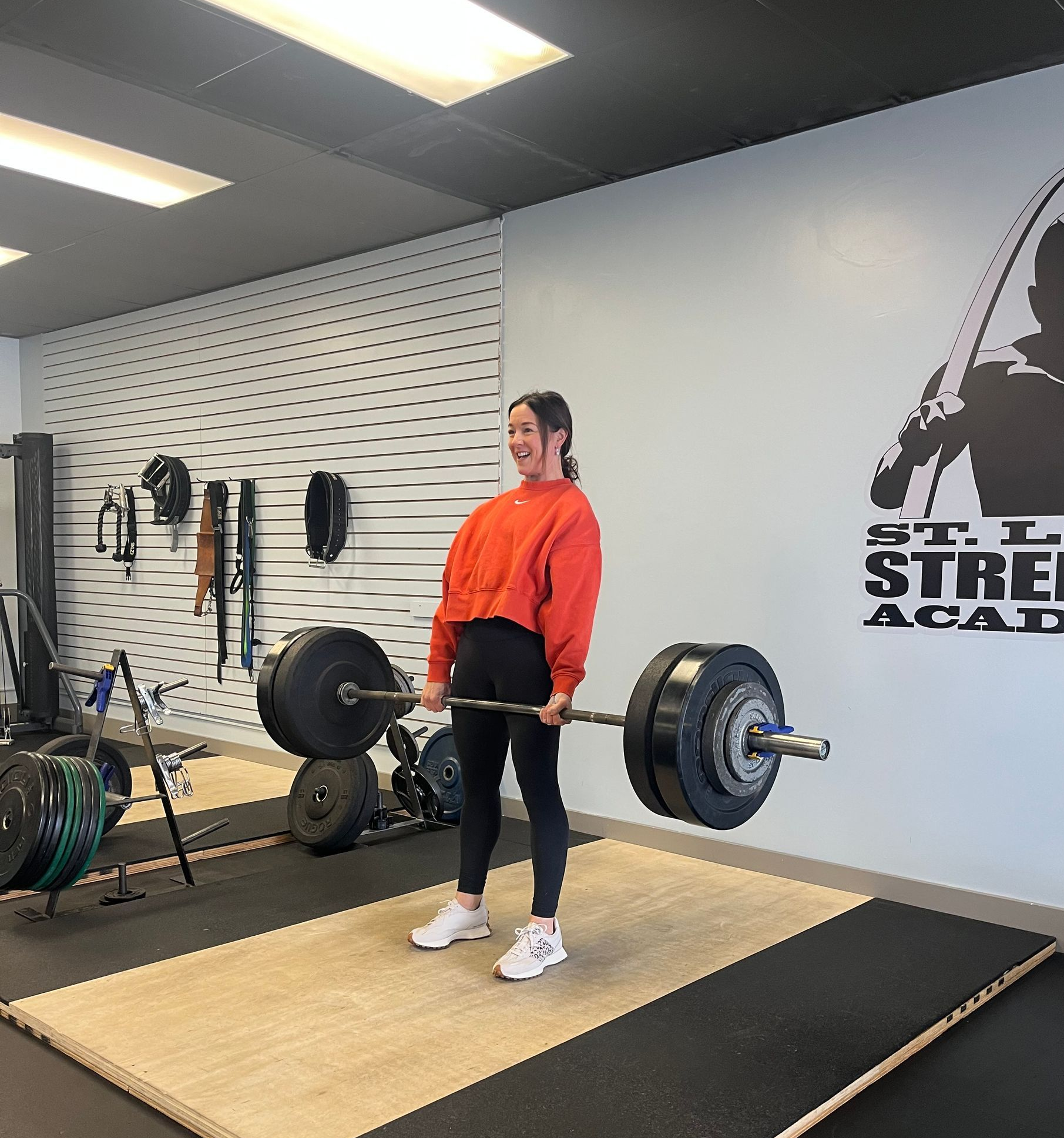 A man is helping a woman lift a barbell in a gym