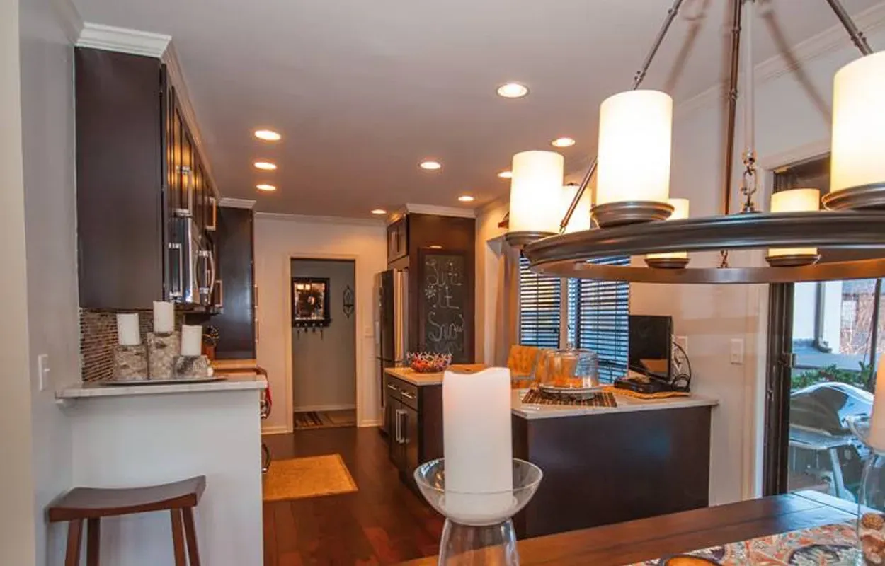 Modern kitchen and dining area with pendant lights, dark cabinets, and a breakfast bar
