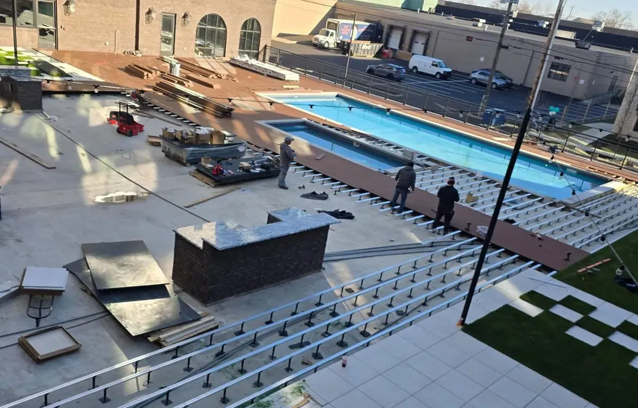 Outdoor pool area with a blue lap pool, lounge chairs, and a few people on a sunny terrace