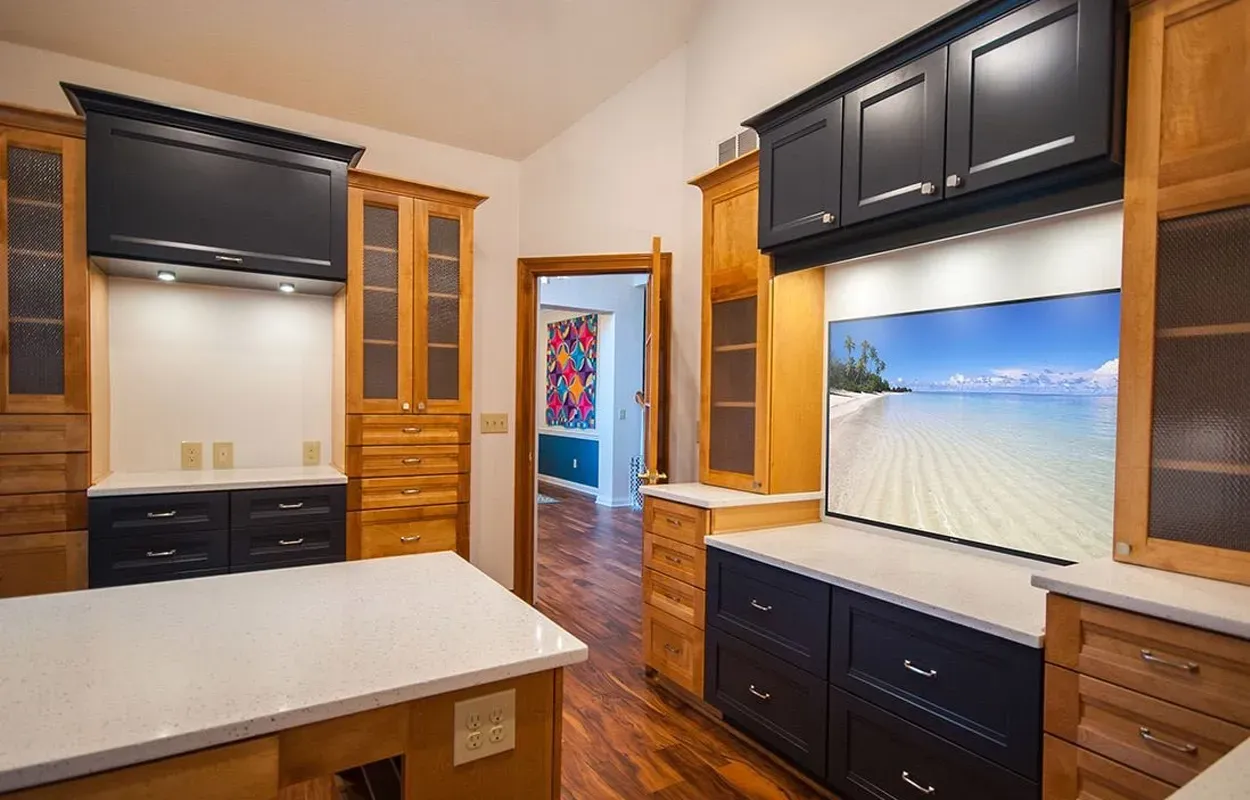 Modern kitchen with dark cabinets, wood trim, and a beach scene on the backsplash screen