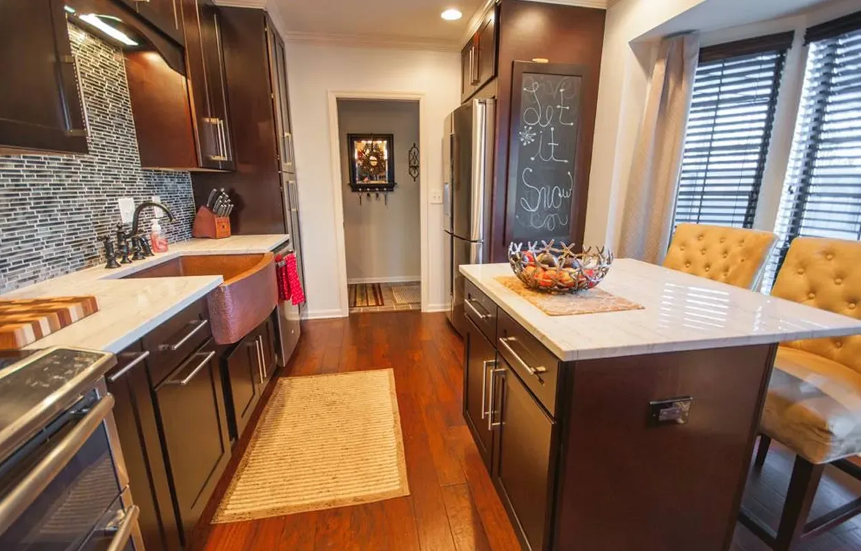 Modern kitchen with dark wood cabinets, stainless appliances, island, and warm hardwood floors