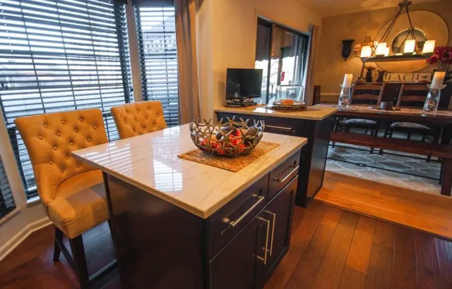 Modern dining room with a marble table, yellow chairs, and warm wood flooring