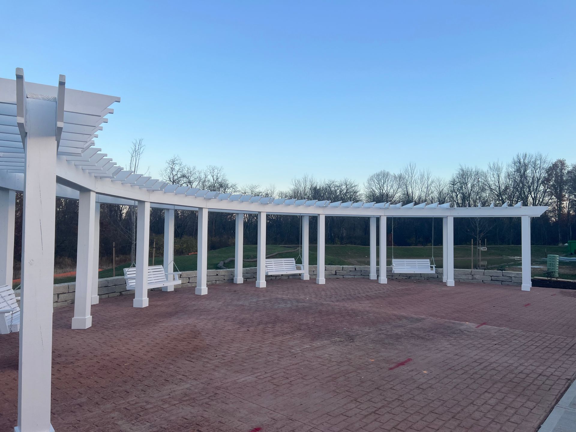 Curved white colonnade around a brick courtyard under a clear blue sky