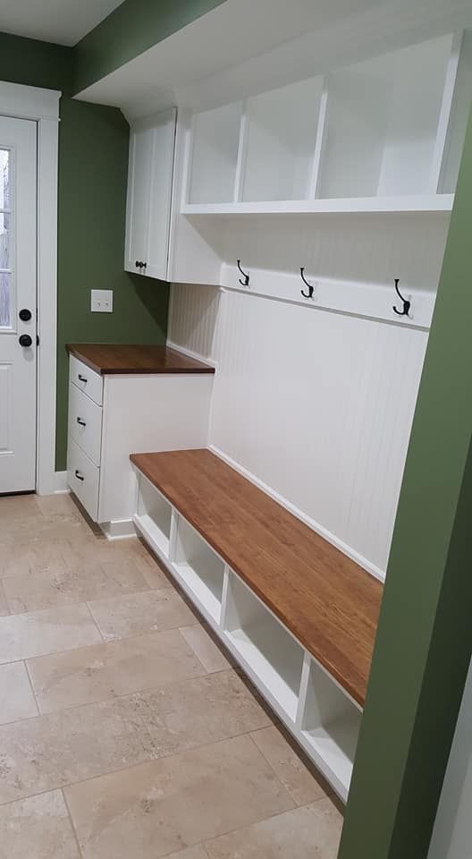 Entryway mudroom with white cubbies, hooks, built-in bench, and green walls.