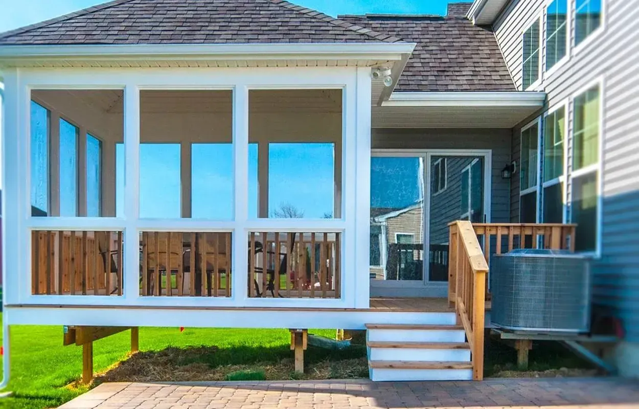 Covered porch with white railings, steps, and blue siding on a house.