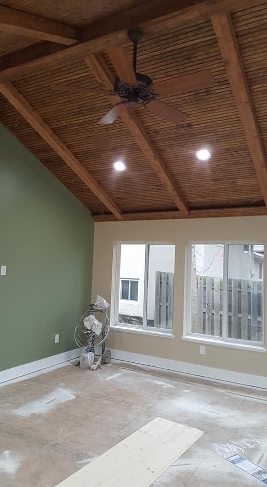 Empty room with green walls, wood-paneled vaulted ceiling, recessed lights, and sliding glass doors.