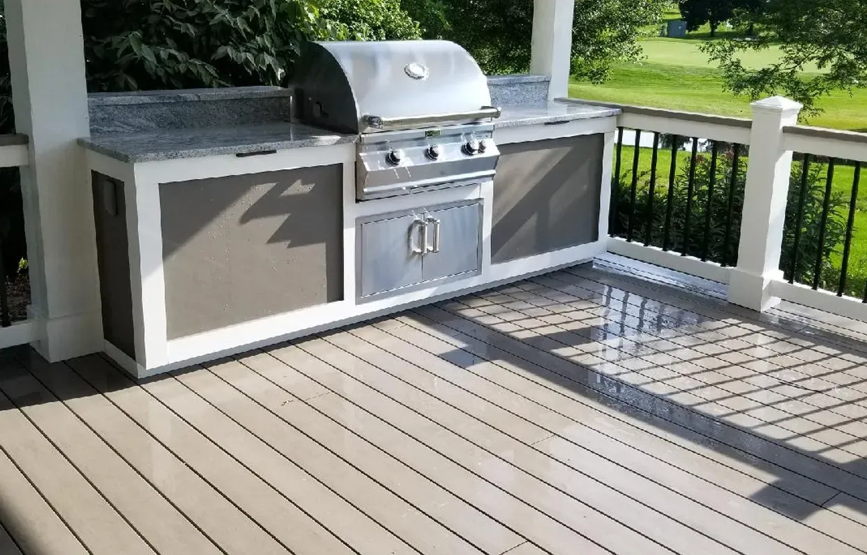 Outdoor patio with built-in stainless steel grill and cabinets on a wooden deck