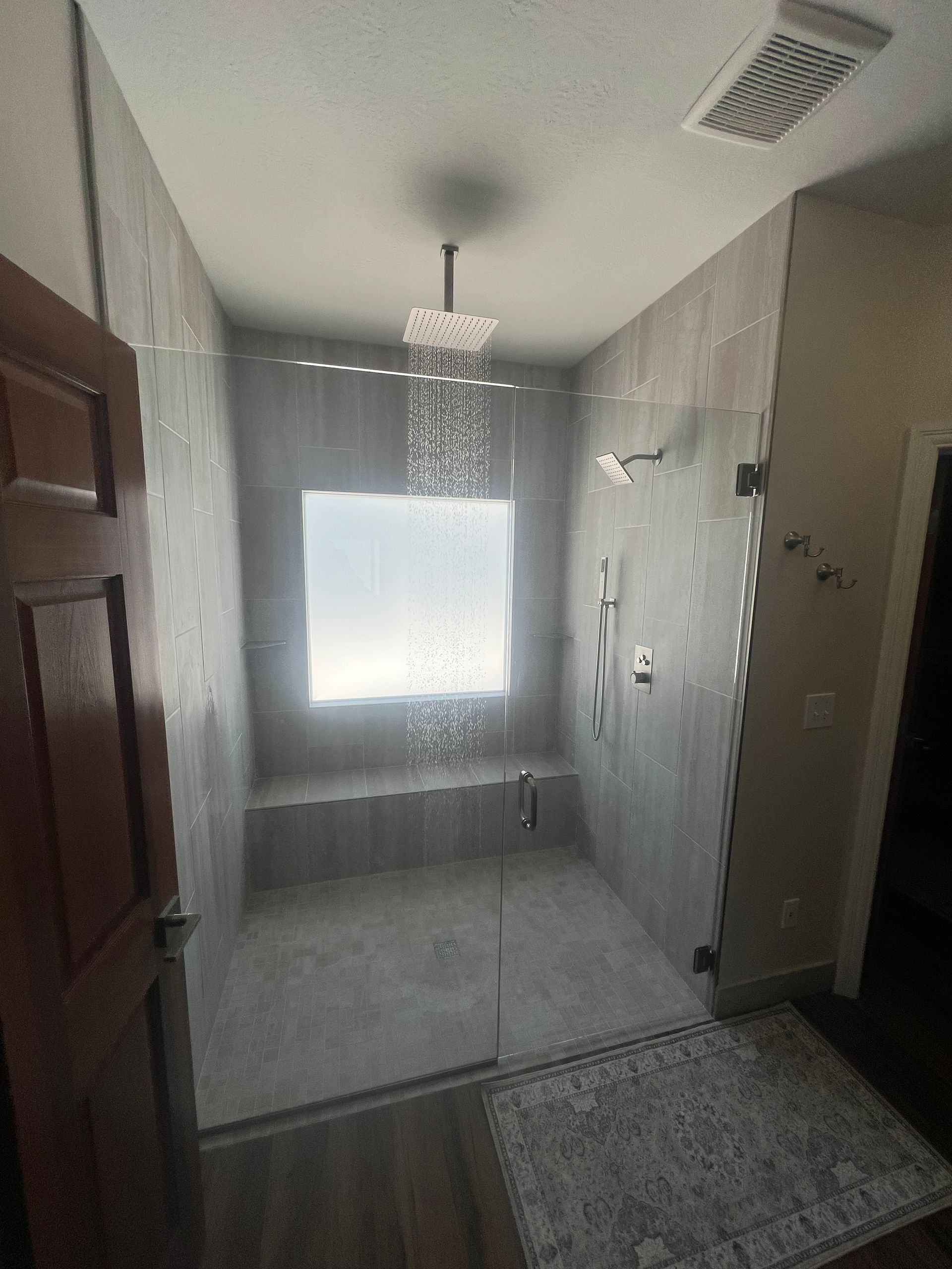 Narrow hallway with a bright window, tiled walls, chandelier, and patterned floor runner