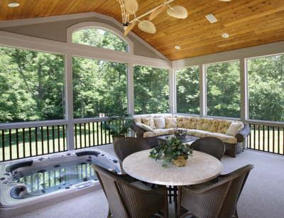 Sunroom with hot tub, round table, and curved sofa overlooking trees