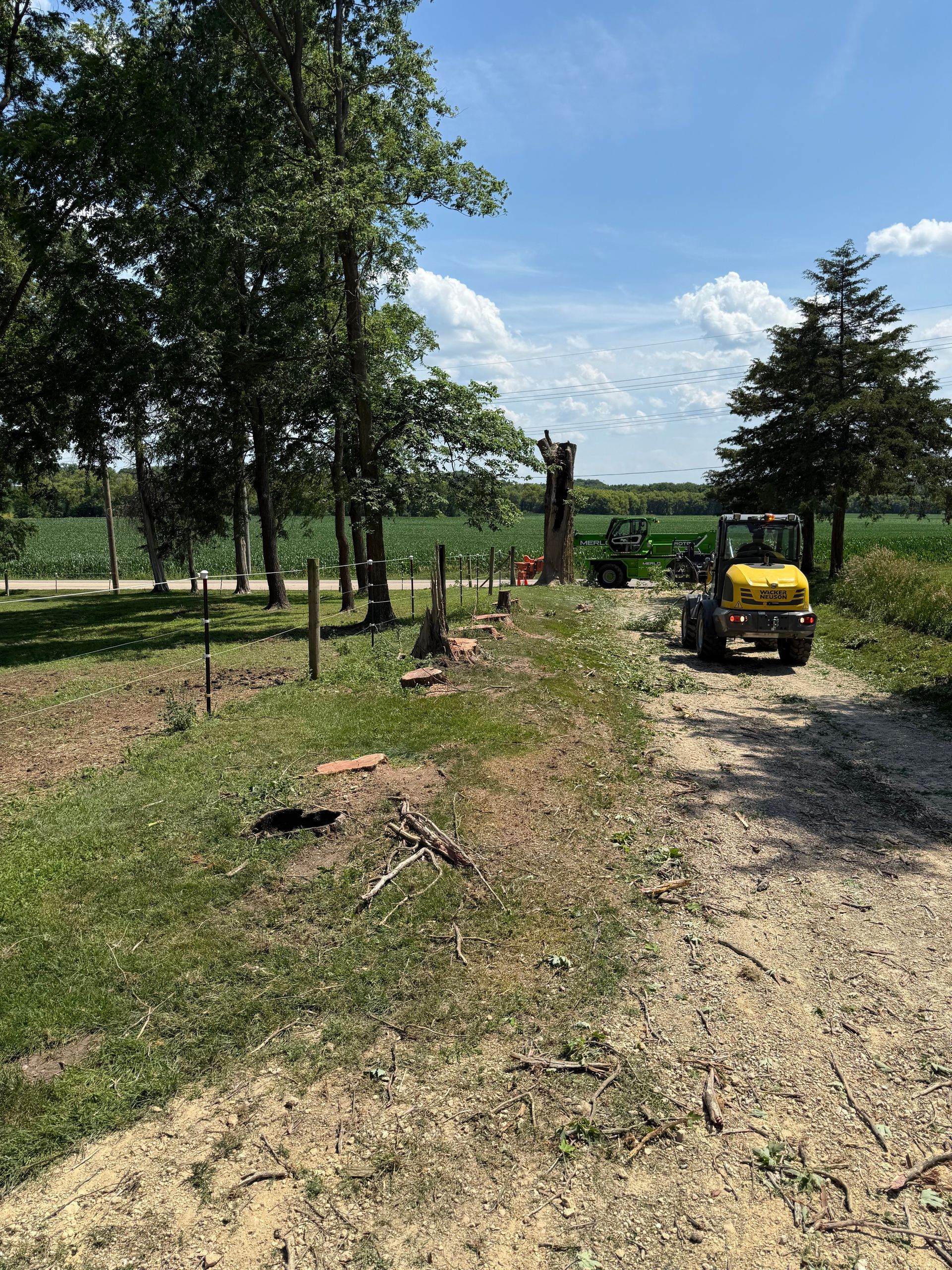A yellow tractor is driving down a dirt road.