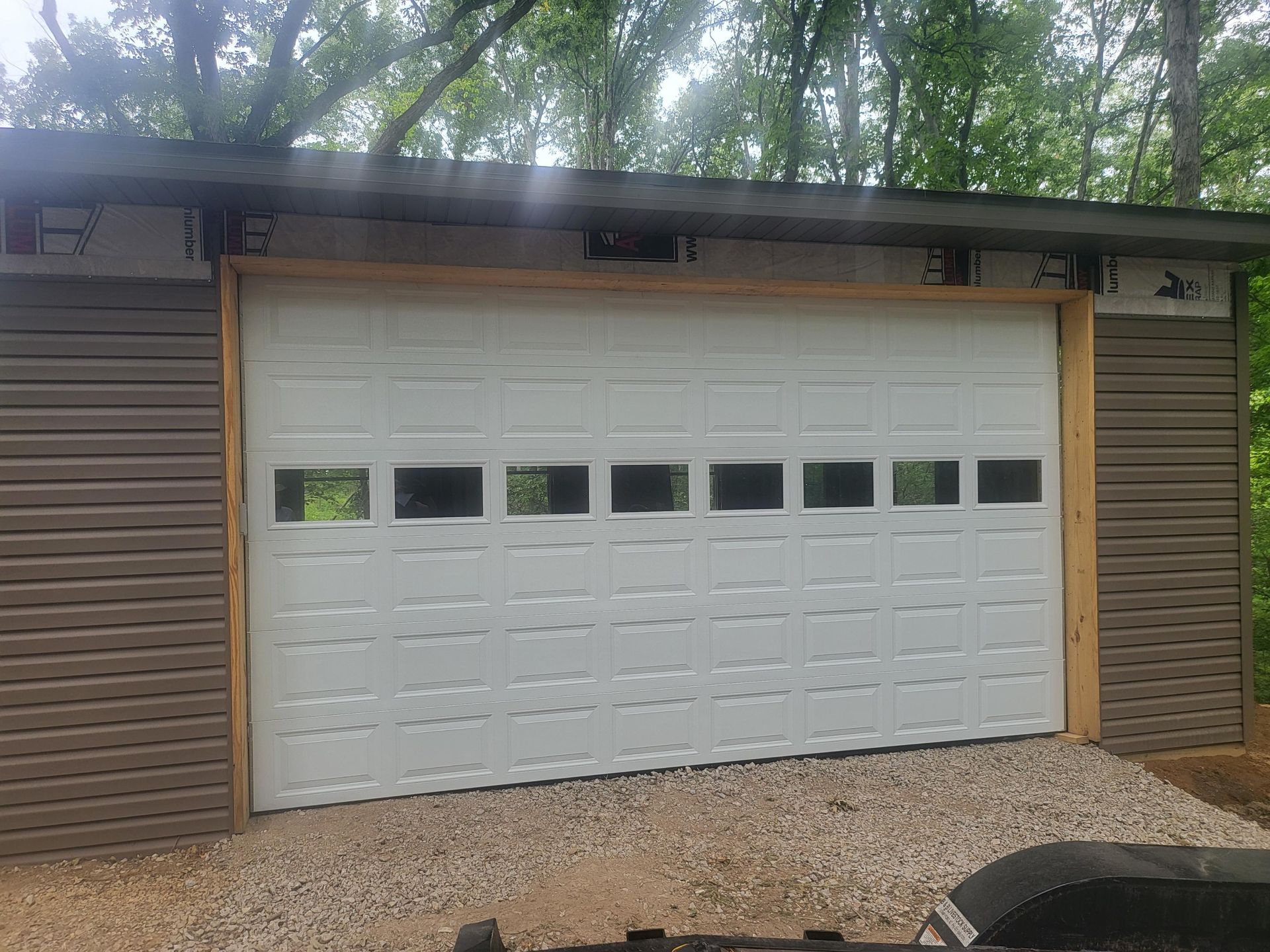 A white garage door is sitting on top of a gravel driveway.