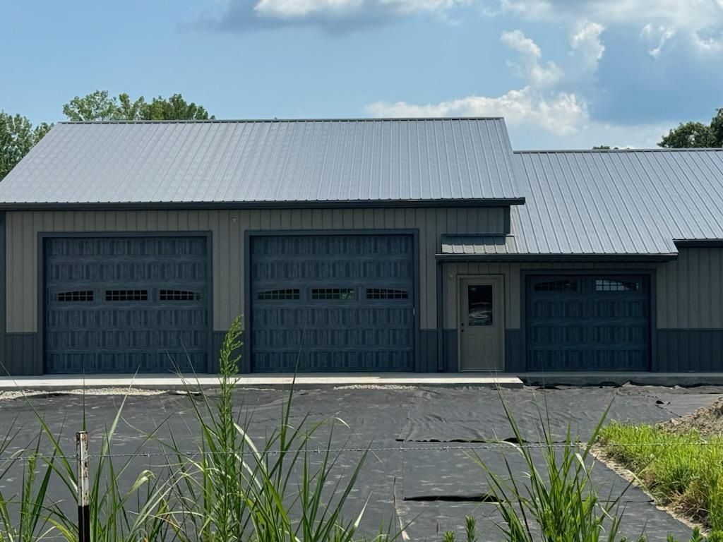 A large building with three garage doors and a gray roof