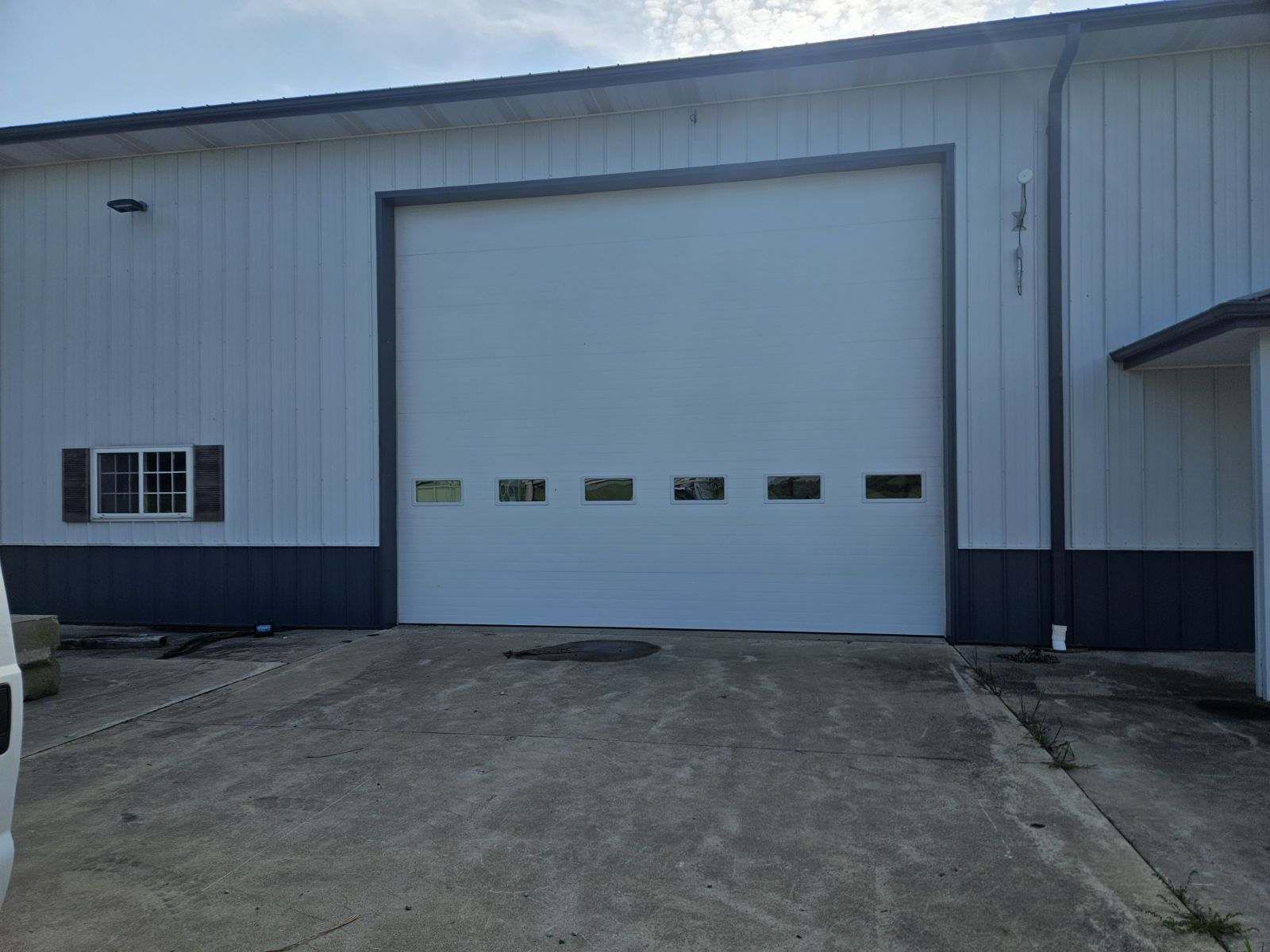 A large white garage door is open on the side of a building.