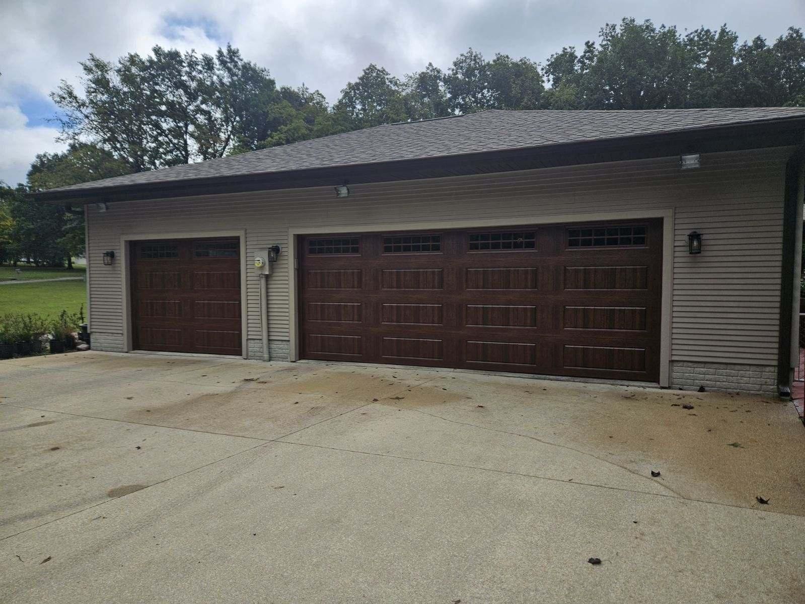 A house with three garage doors and a car parked in front of it.