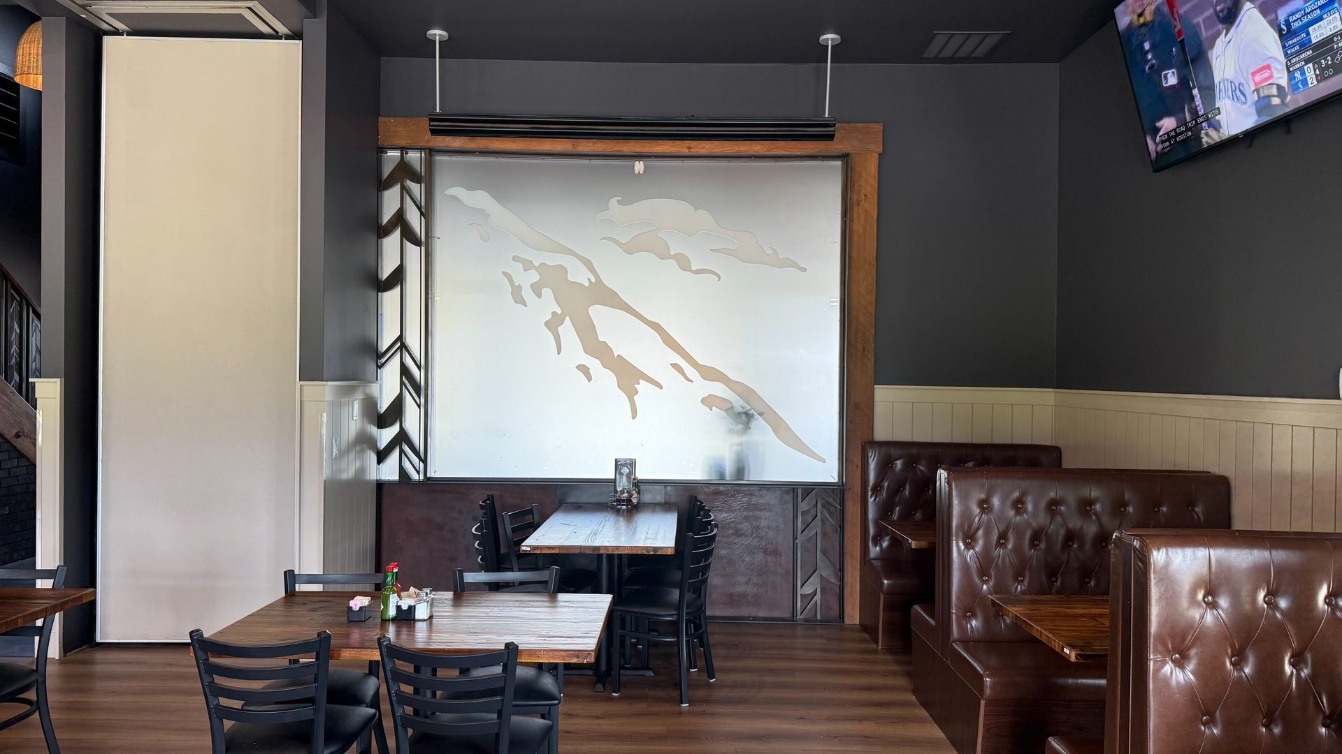 A restaurant with tables and chairs and a large screen on the wall