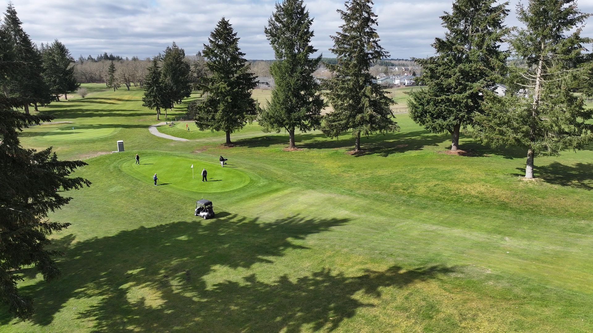 An aerial view of a golf course with trees in the background