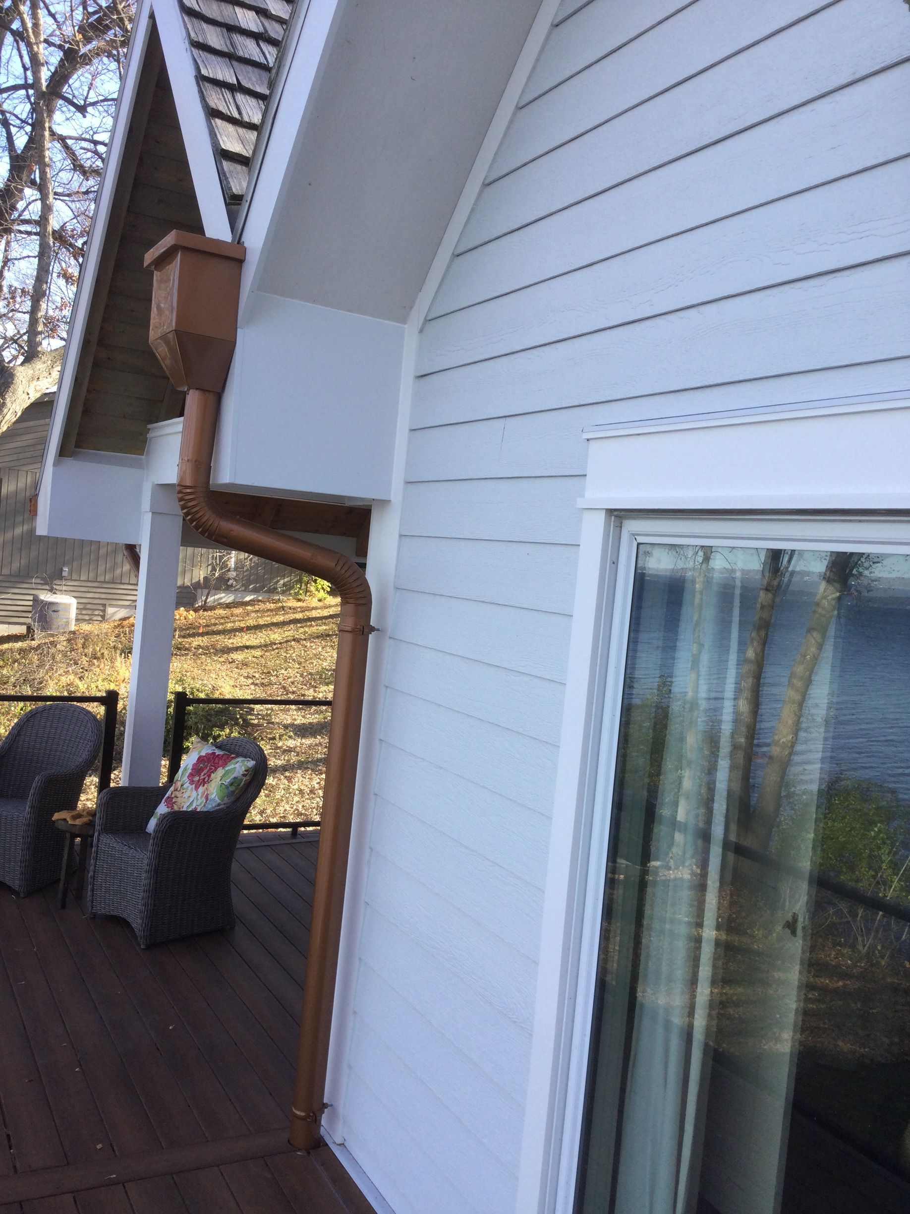 A white house with a copper gutter on the side of it.