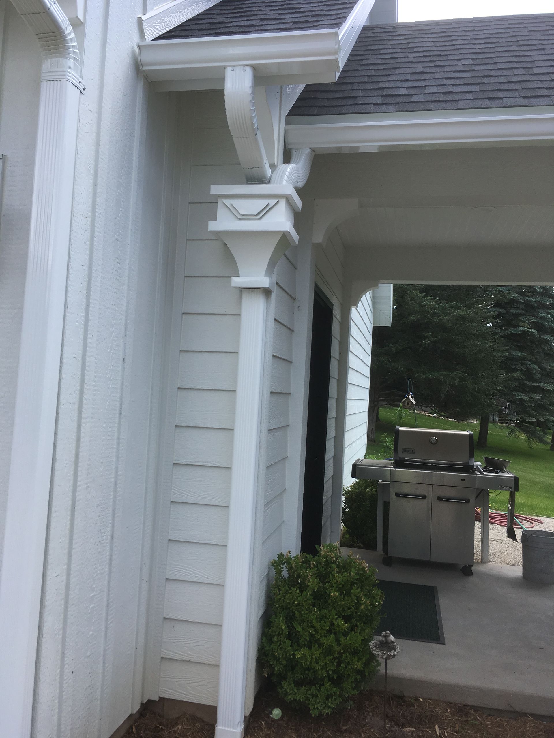 A white house with a gutter on the side of it.