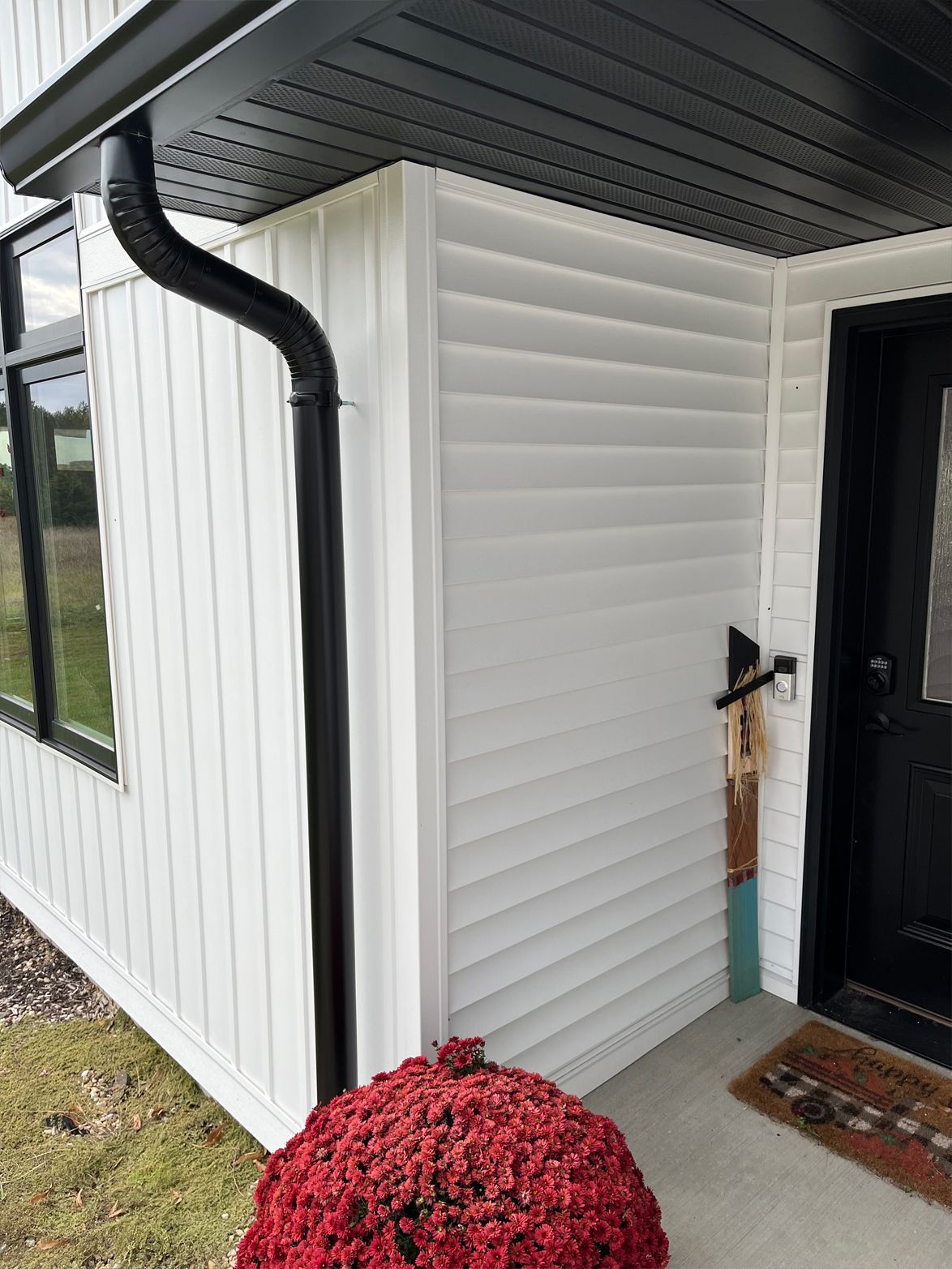 A white house with a black door and a black gutter.