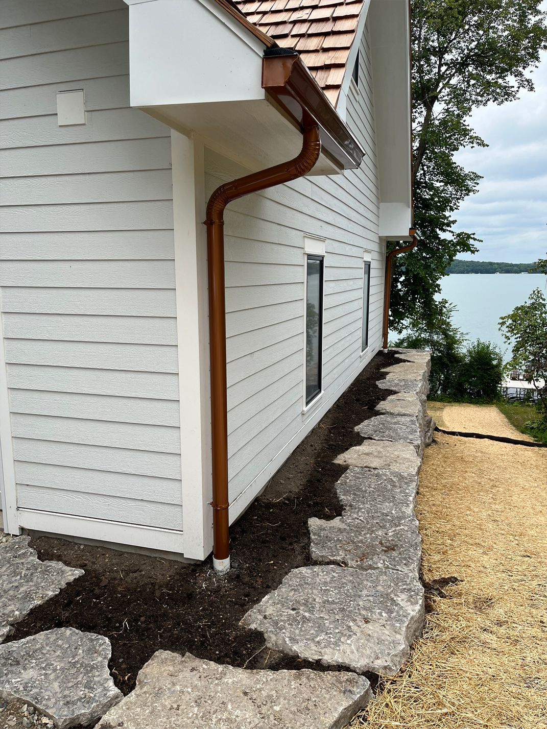 A white house with a copper gutter on the side of it.