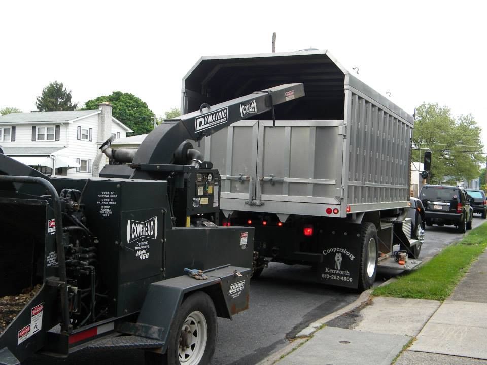 A truck with a chipper attached to it is parked on the side of the road.