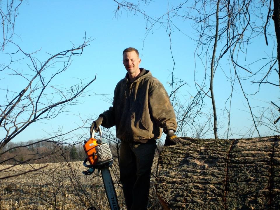 A man is holding a chainsaw in a field