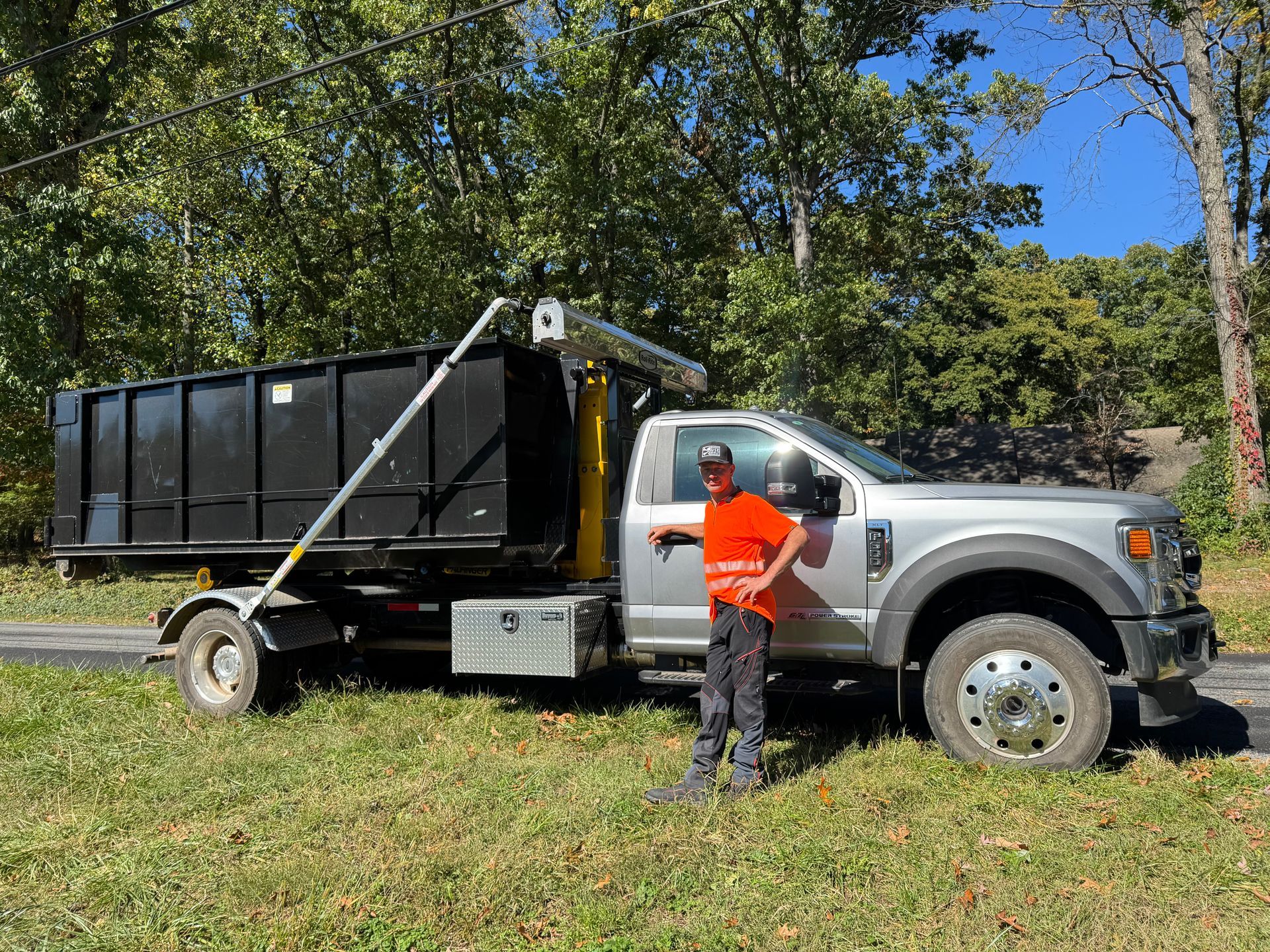 A man is standing in front of a dump truck.