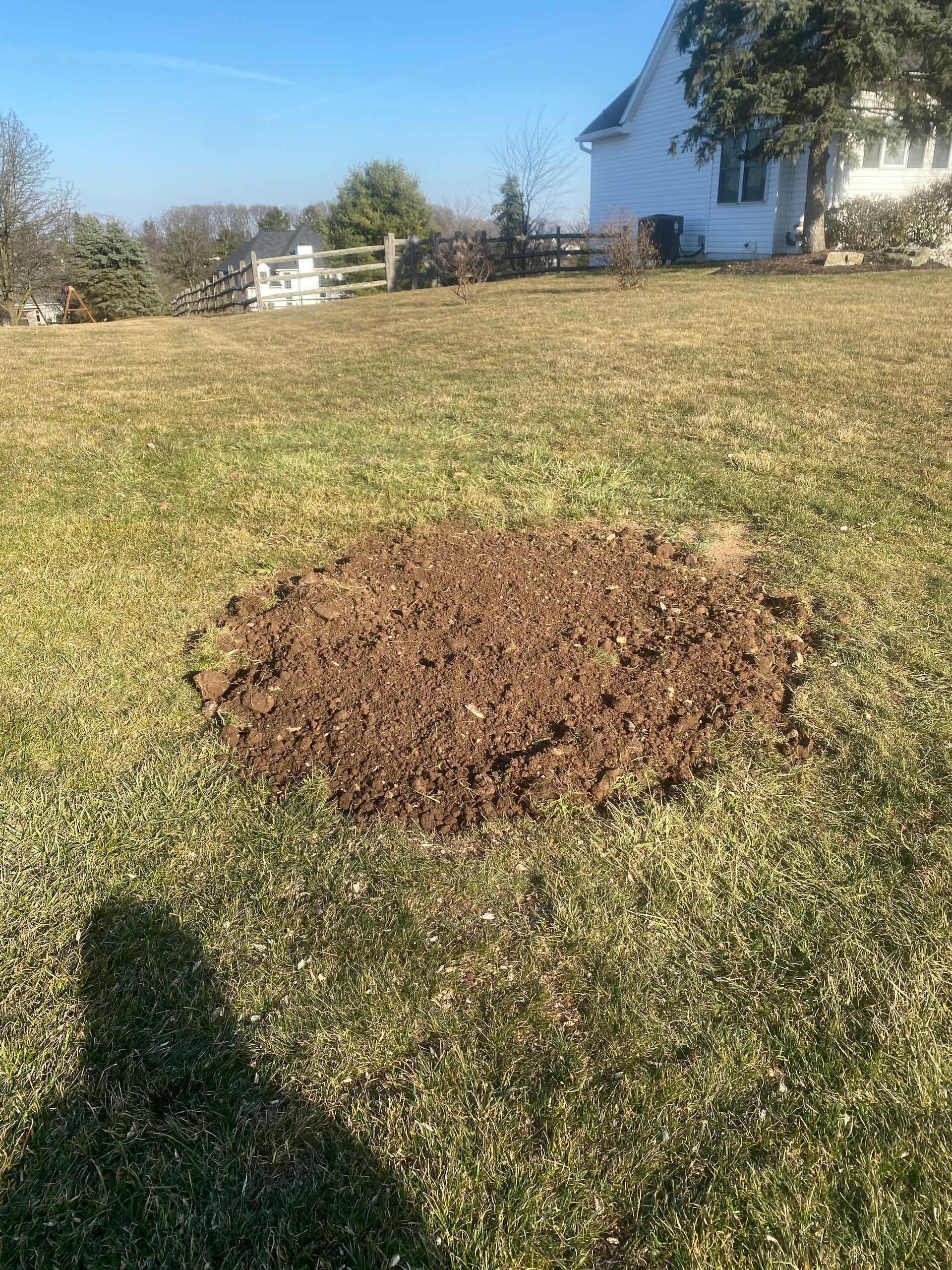 A large pile of dirt is sitting in the middle of a grassy field.