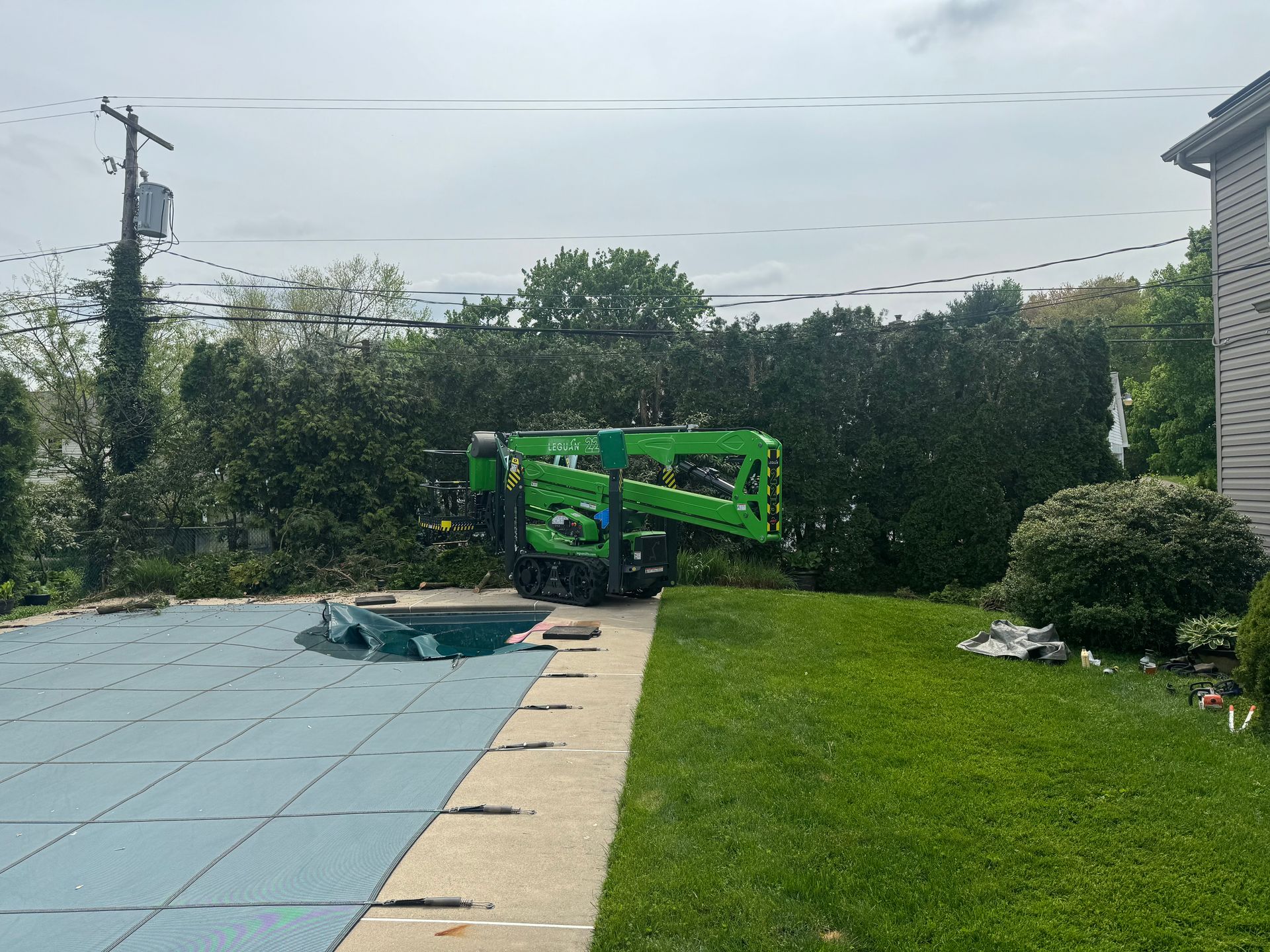 A green crane is sitting next to a swimming pool.