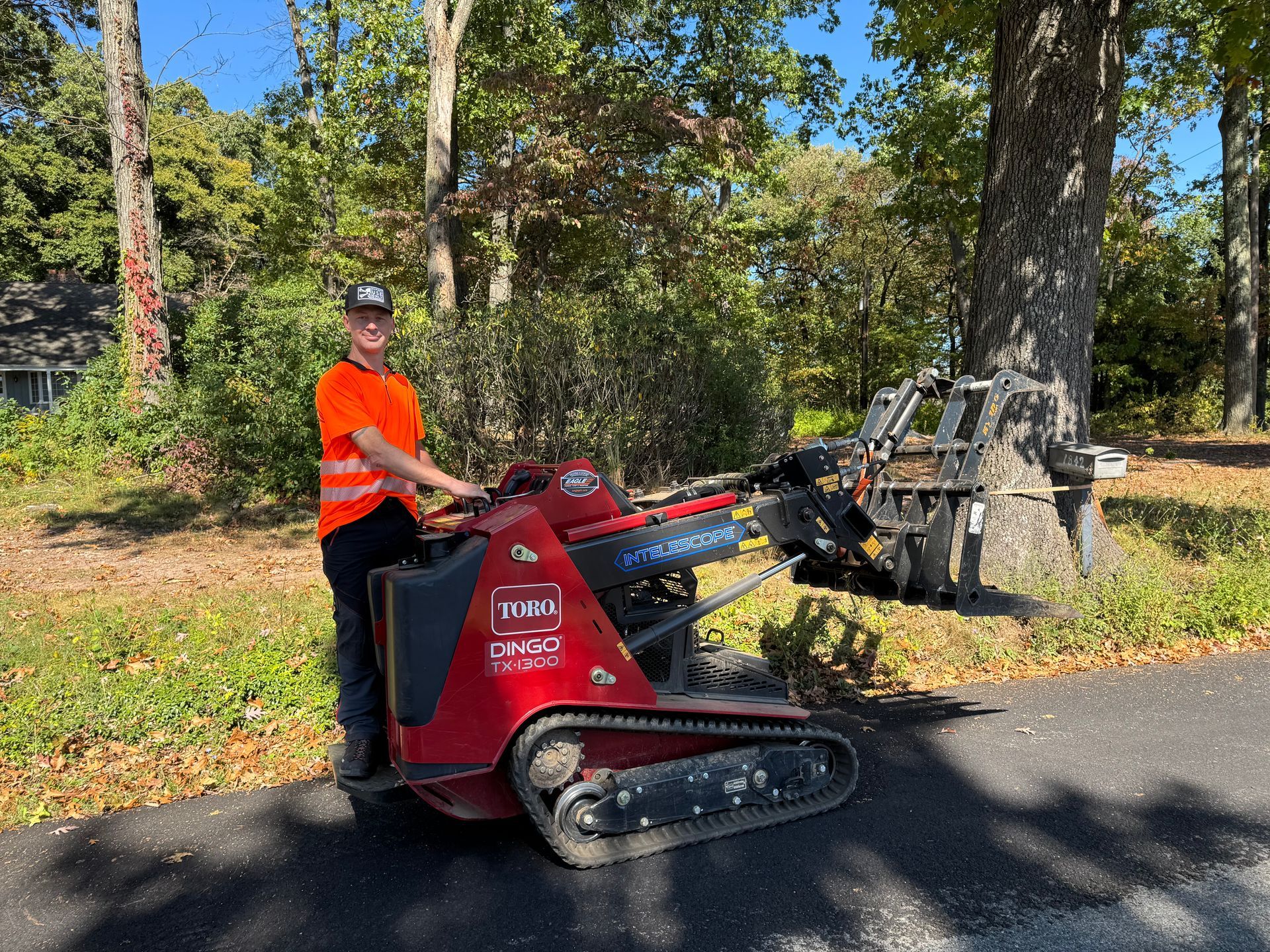 A man is standing next to a red tractor on the side of the road.