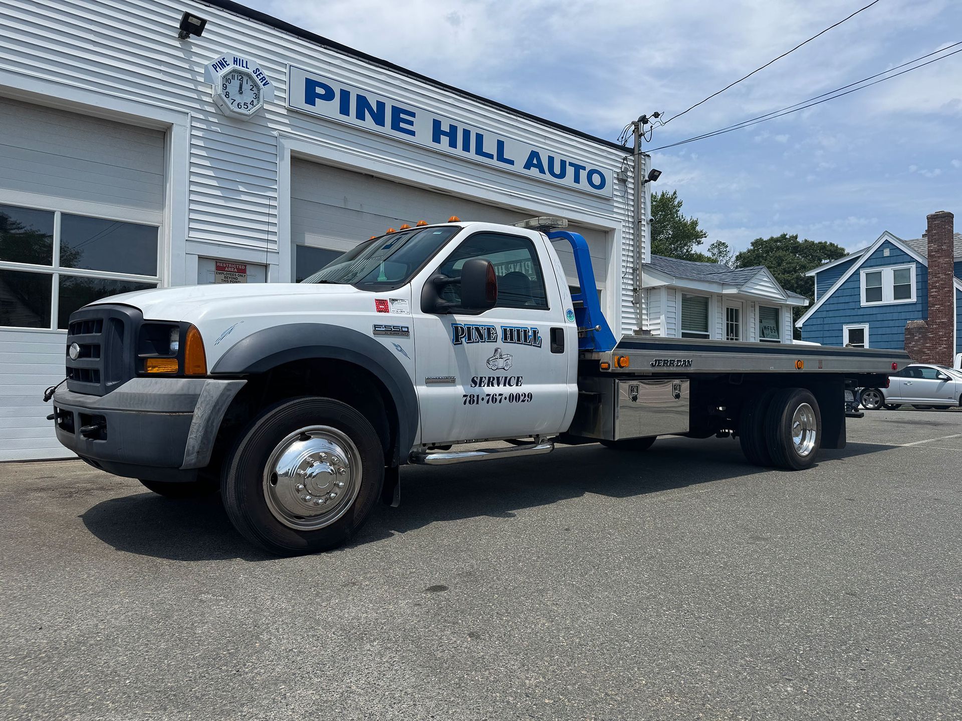 White Pine Hill Auto tow truck parked outside the shop on a sunny day.