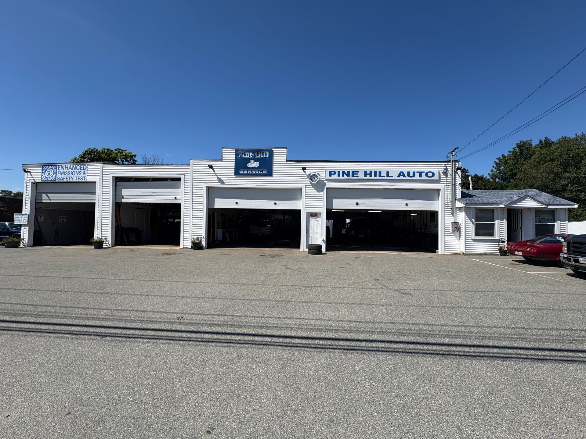 Pine Hill Auto repair shop with open garage doors on a sunny day.