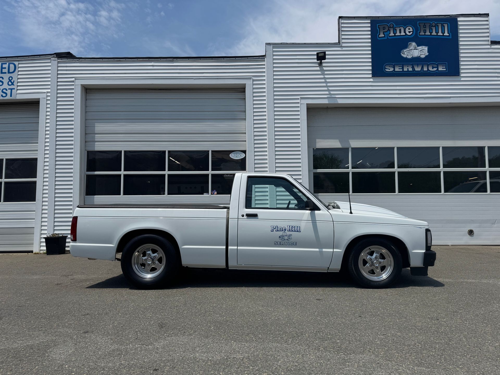 White pickup truck parked outside a garage. Blue Hill Service sign above a garage door.