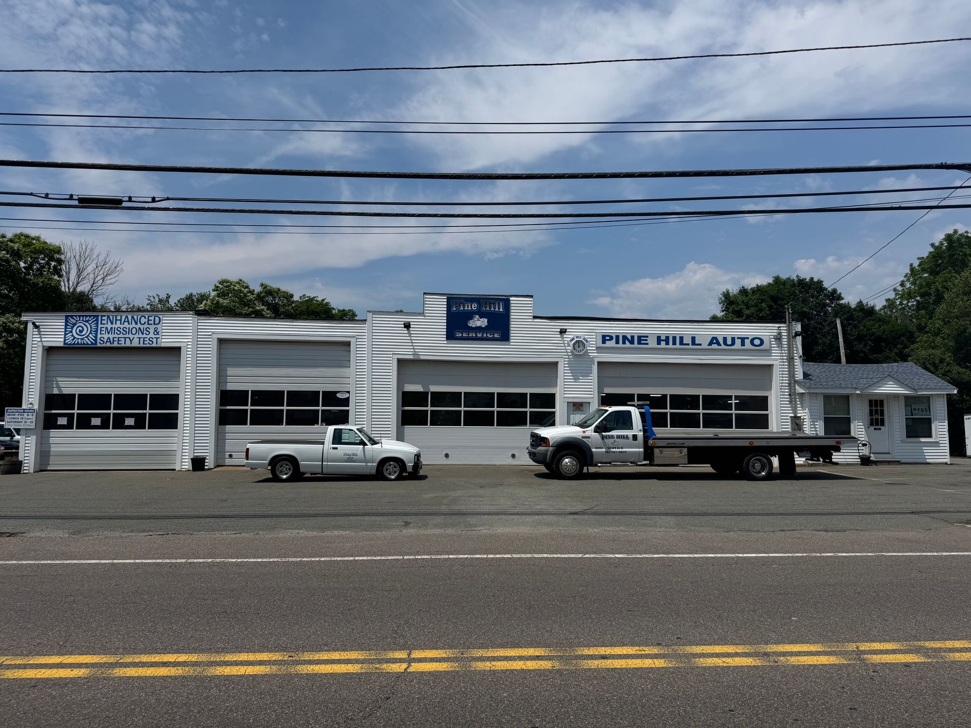 Pine Hill Auto repair shop with two white pickup trucks parked in front.