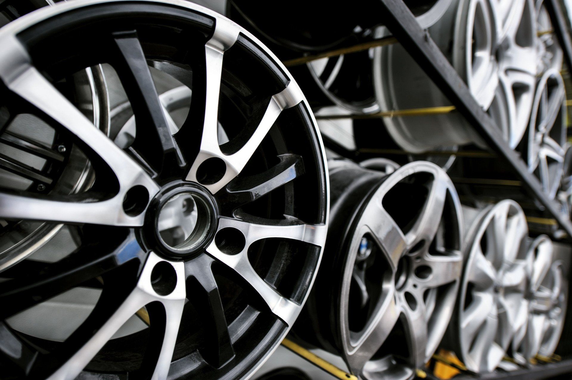 Car alloy wheels displayed on a rack, black and silver rims.